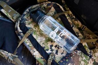 A water bottle on a backpack, hunting in summer tips for staying hydrated concept.