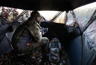A hunter sits in a ground blind, getting a Georgia hunting license concept.