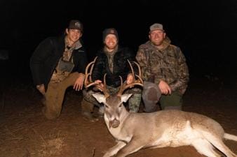 Three hunters smile with a deer after a successful hunt, meat for holiday venison recipes concept.