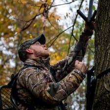 A deer hunter setting up a tree stand.