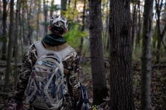 A hunter in the woods with essential hunting gear.