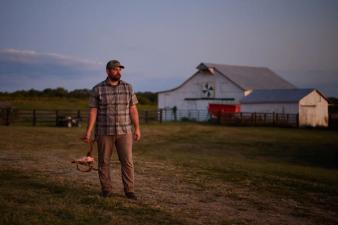 Hunter stands in field holding deer skull, find free hunting land near me concept.
