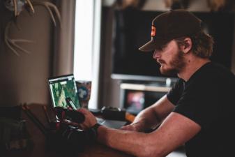 A man looks at a computer with HuntWise on the screen, e scouting for elk concept.