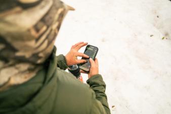 Hunter using phone with HuntWise on screen, how to find mule deer concept.