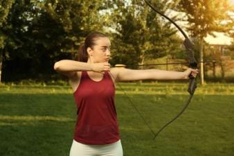 A woman draws a recurve bow.