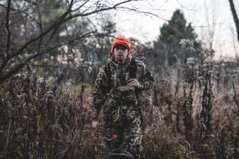 A hunter walking in the brush while wearing camo, get ready for opening day of gun season concept.