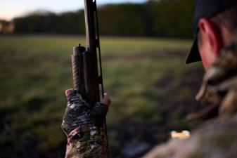 Hunter with shotgun and HuntWise app, best dove hunting shotgun concept.