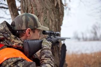 A hunter aims a rifle, choosing the right gun calibers concept.