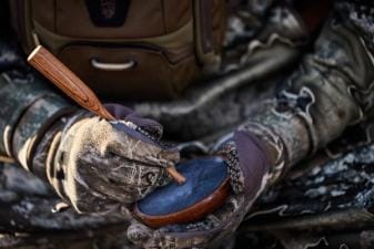 A hunter with camera equipment using HuntWise in the field, hunting influencer concept.
